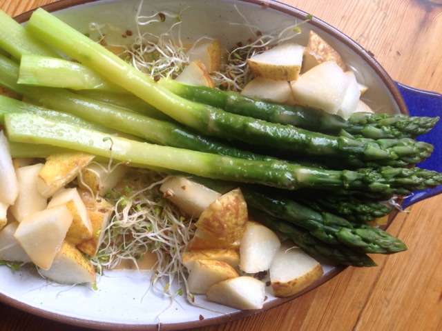 Delicious fresh green asparagus on a bed of alfalfa with pear pieces, served with citrus dressing