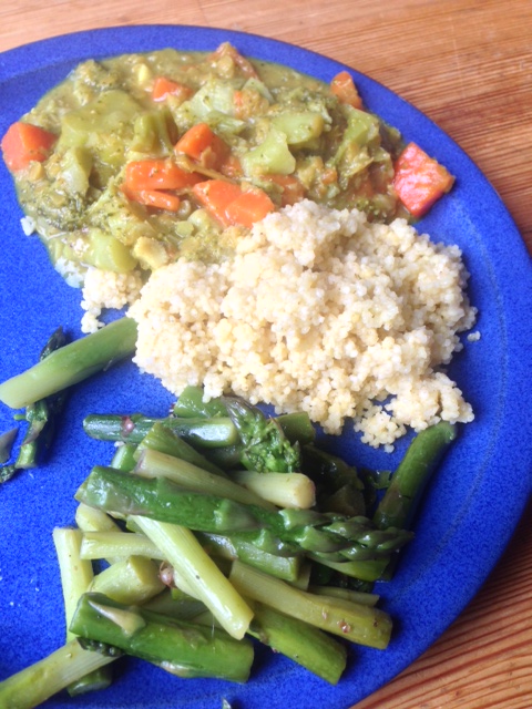 Carrot and broccoli pan with coconut milk and curry, served with millet and green asparagus